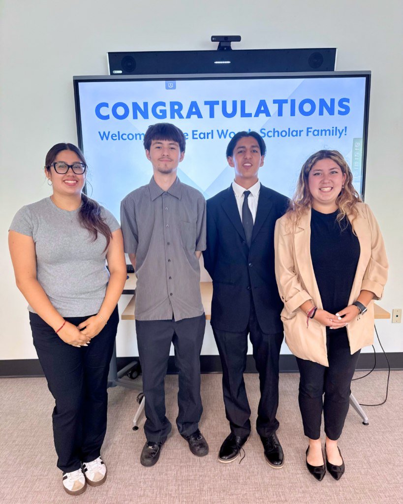 Four students pose in front of a screen that reads 'CONGRATULATIONS' and welcomes the Earl Warren Scholar Family.